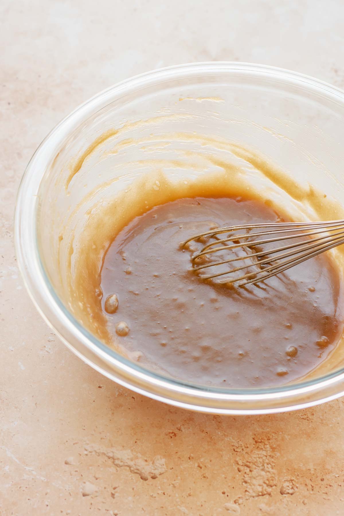A whisk mixes sugar and butter in a bowl.