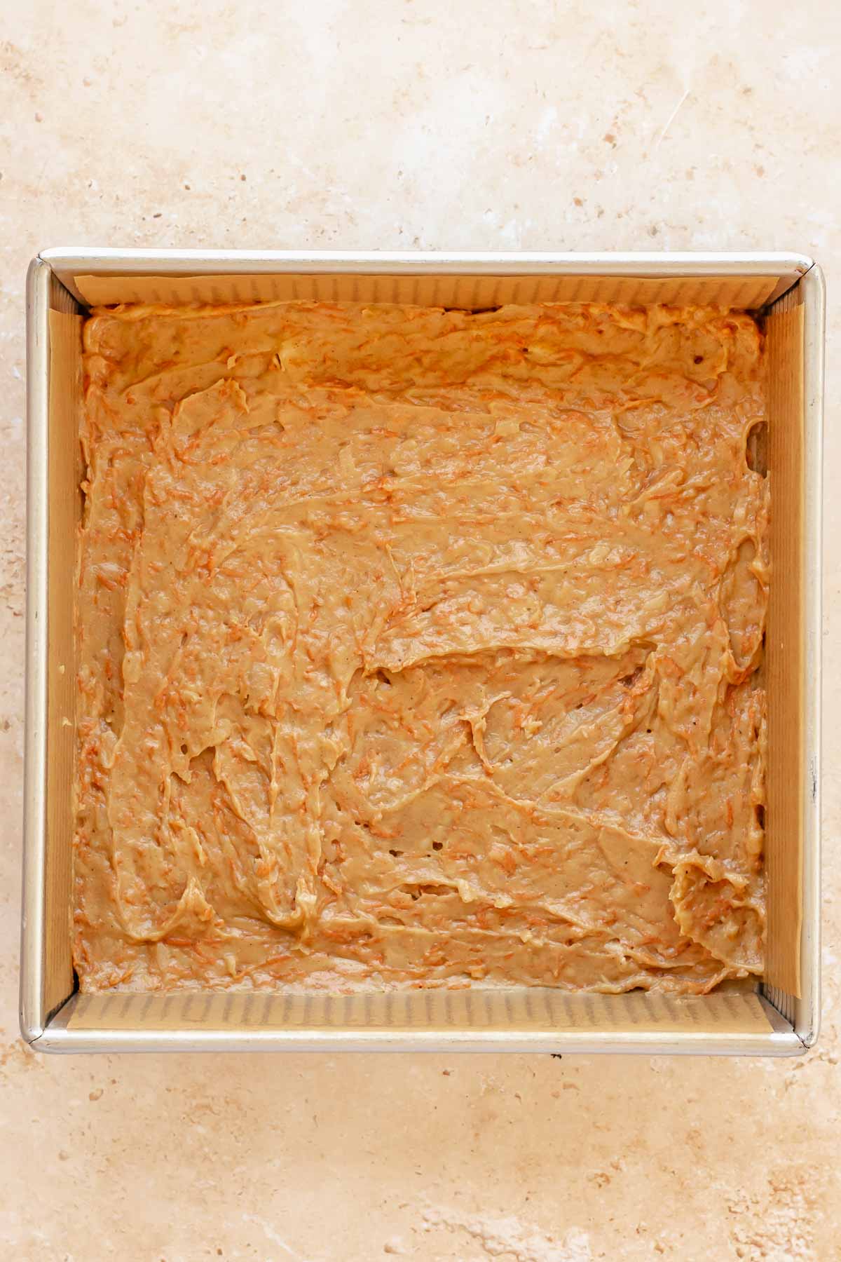 Carrot cake batter spread into a square pan.