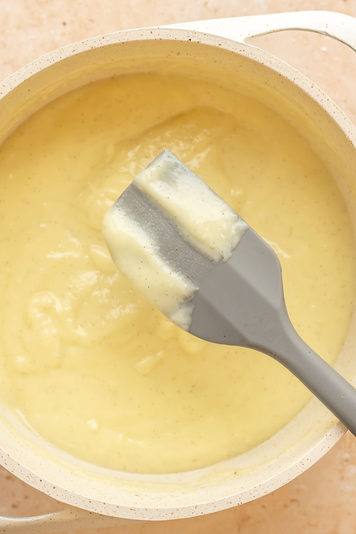 A spatula covered in pastry cream with a swipe removed to show consistency.