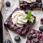 Blueberry pie bar squares with whipped cream and mint springs.