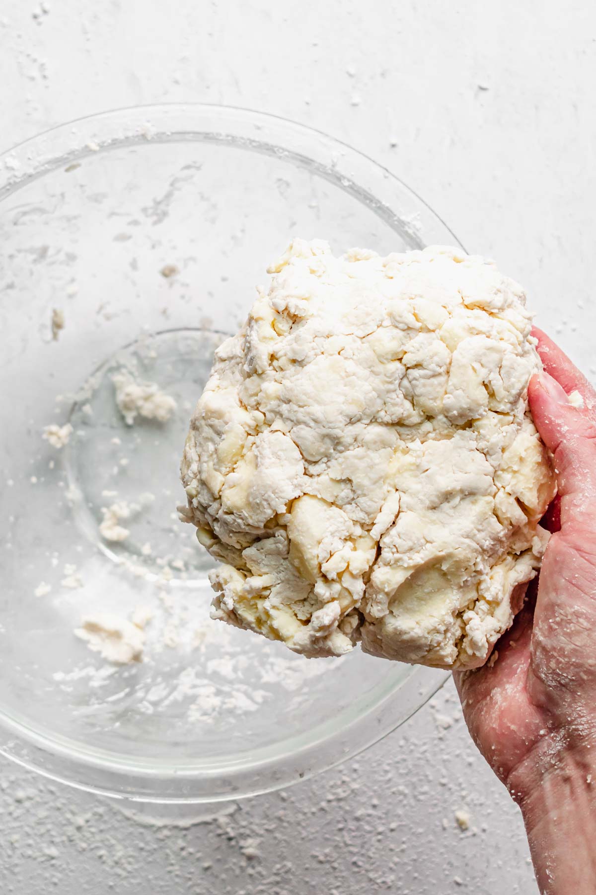A hand holds the dough in a form.
