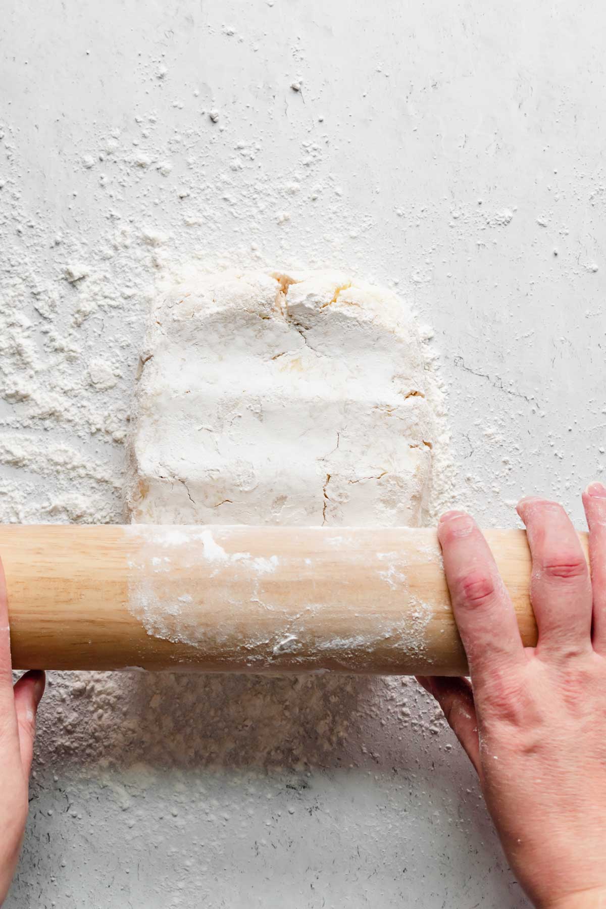 A floured rolling pin begins to roll out the dough.