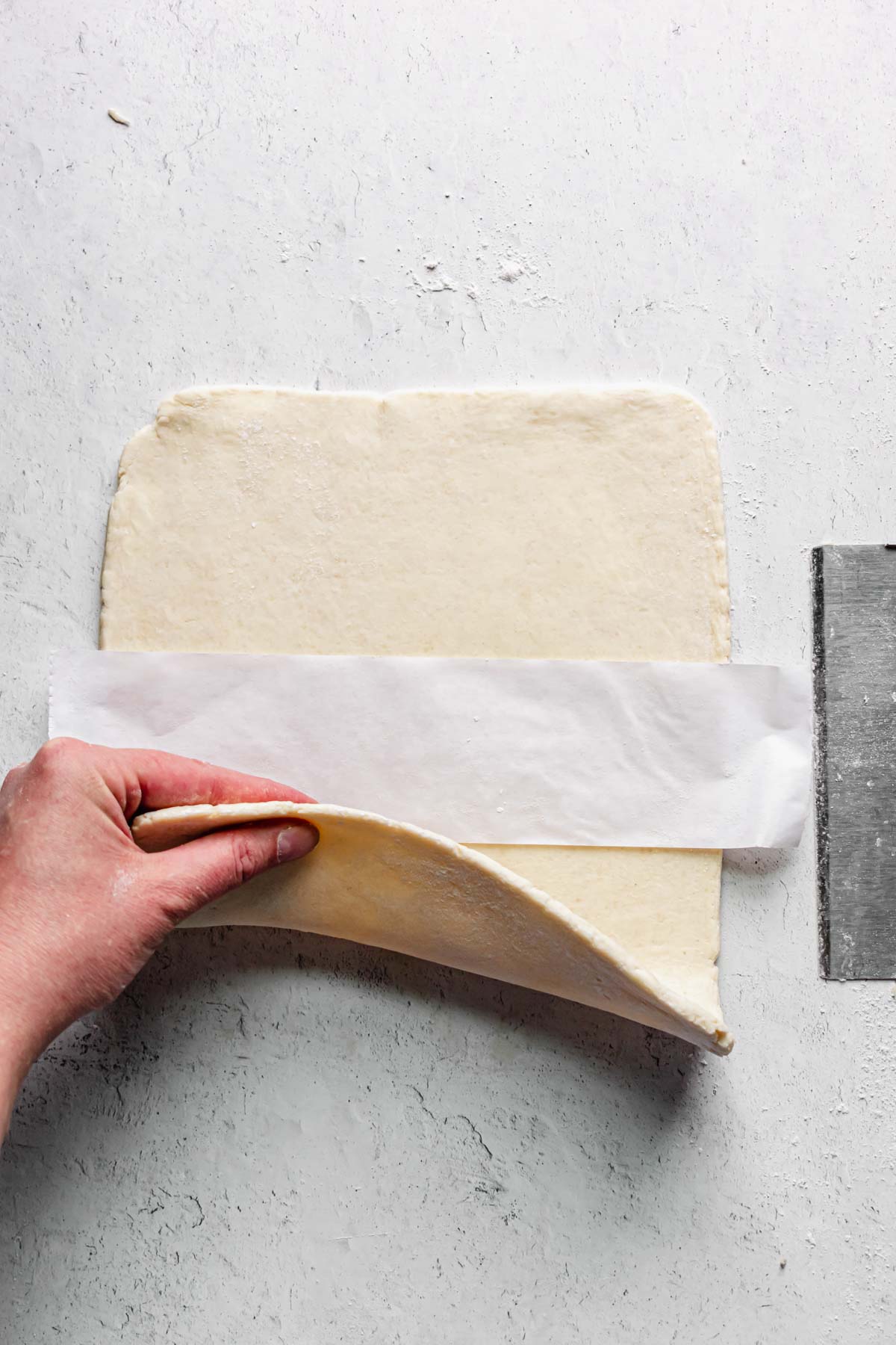 A strip of parchment paper is added to the center of the rolled out dough.