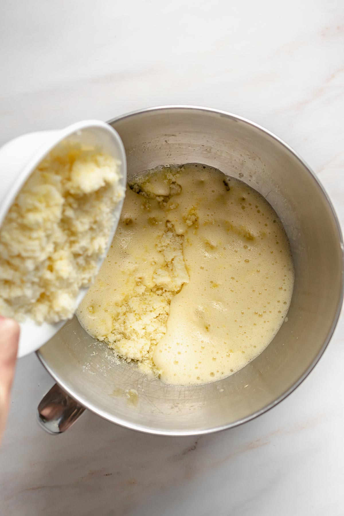 Lemon zest sugar pouring into whipped eggs.