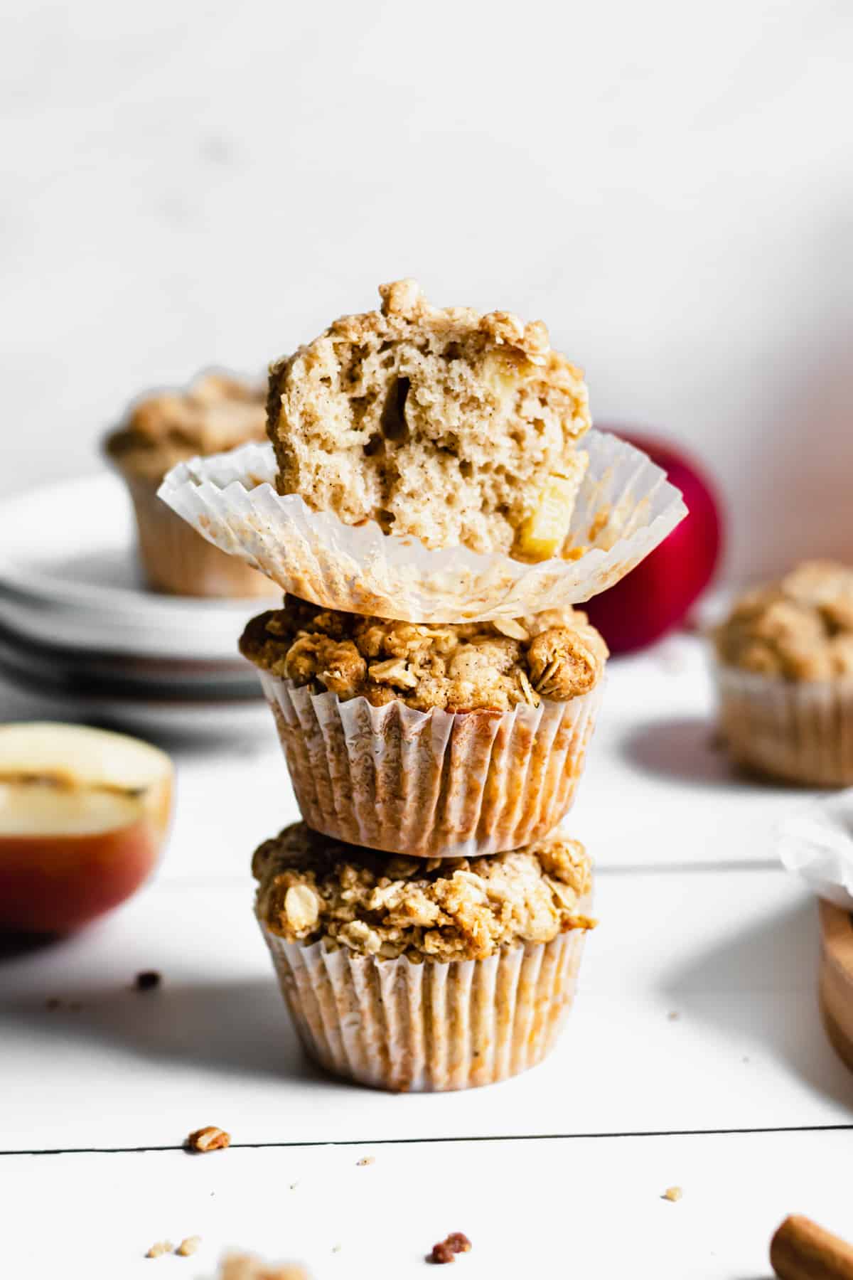 stack of three apple streusel muffins. the top muffin has a bite removed