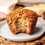 A banana muffin on a plate with a bite removed.