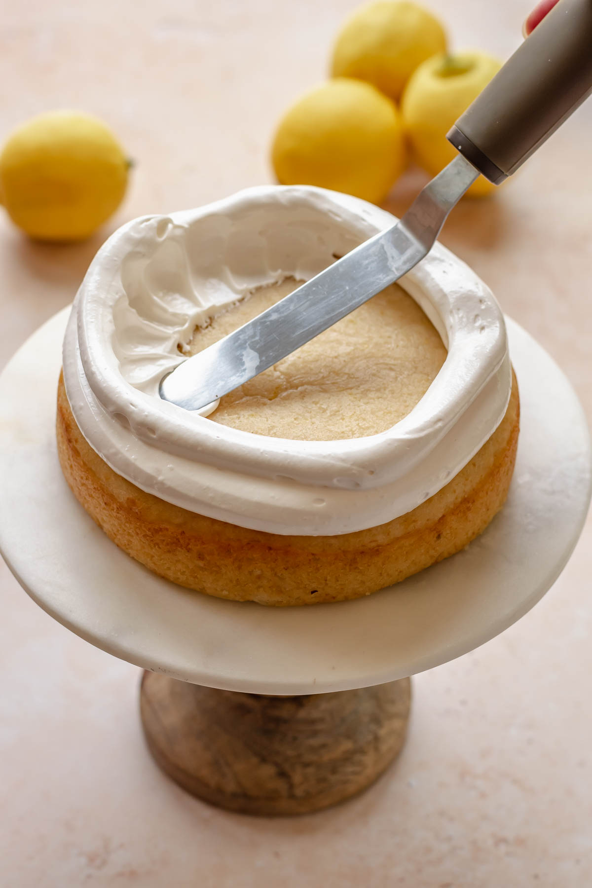 An offset spatula pulls meringue into the center of the cake.