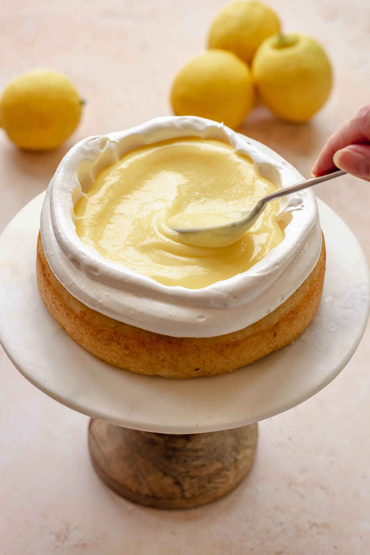 A spoon adds lemon curd into the middle of the cake.