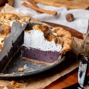 A slice of purple sweet potato pie in a pie dish.