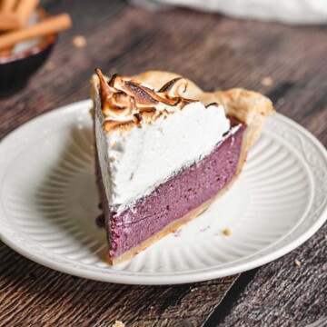 A slice of purple sweet potato pie with toasted meringue on a plate.