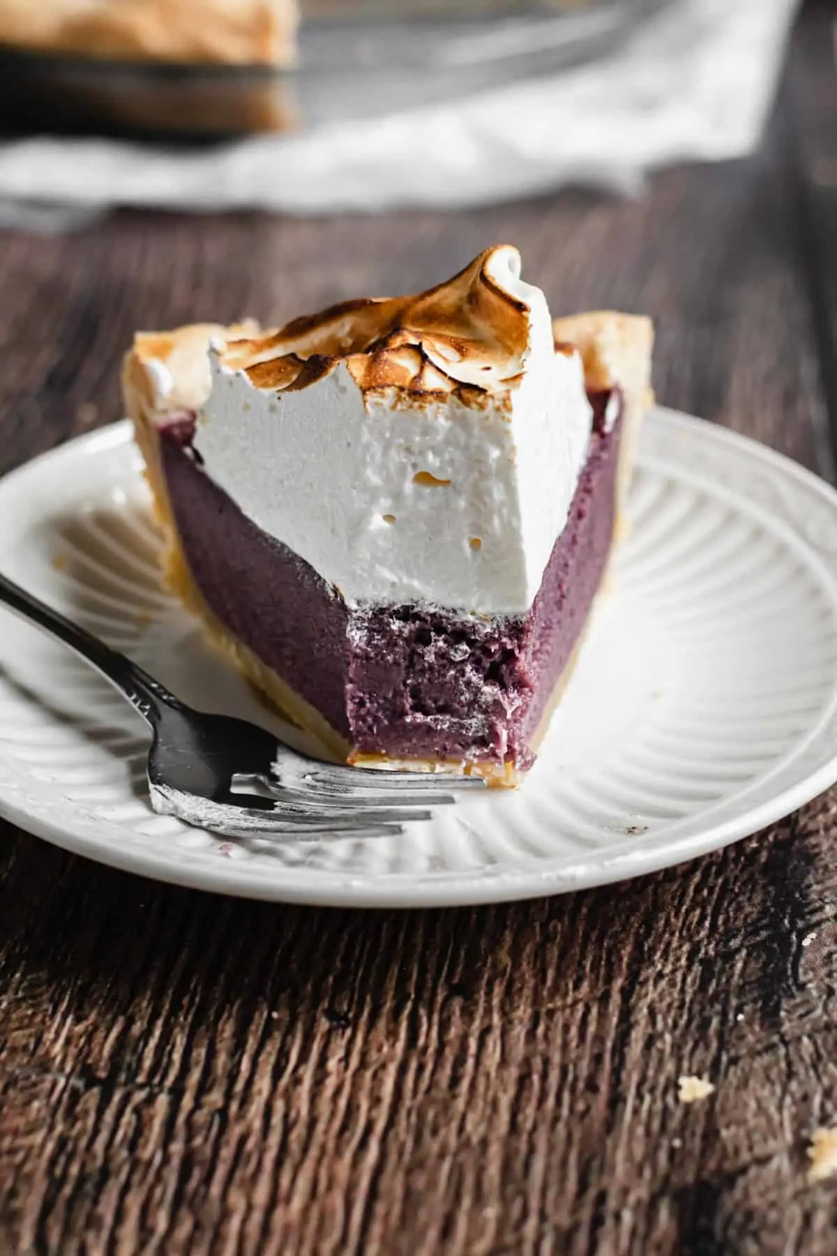 One slice of purple sweet potato pie on a plate with a bite removed