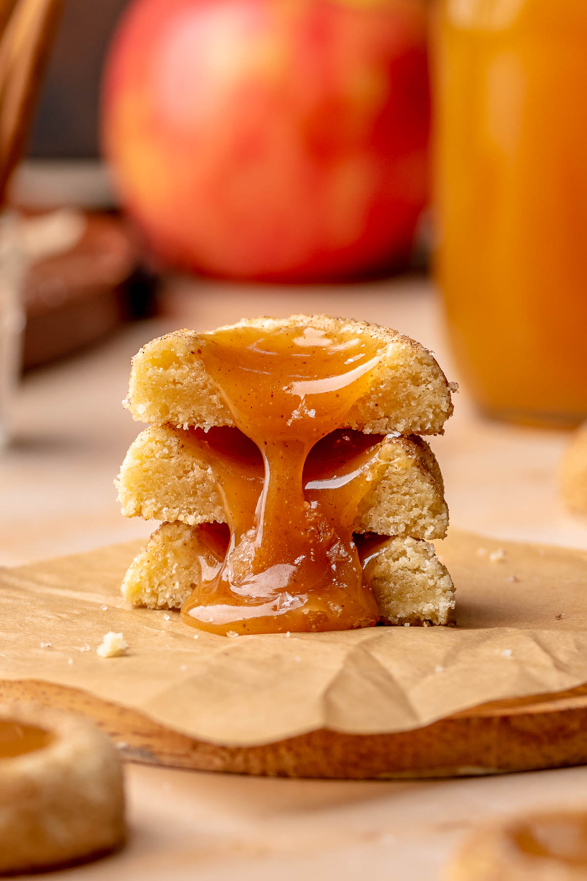 A stack of apple cider cookies cut in half with caramel oozing down the stack.