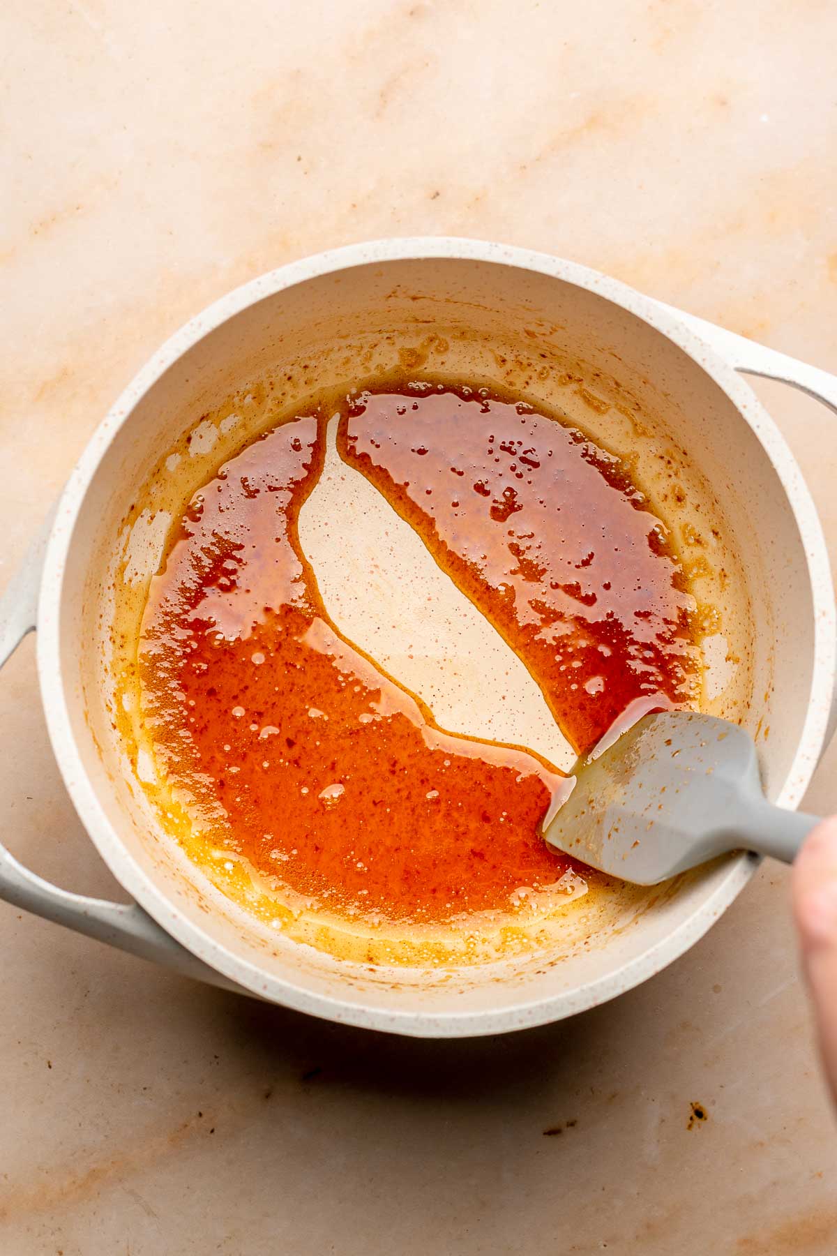 A spatula drags through a pot of reduced apple cider.