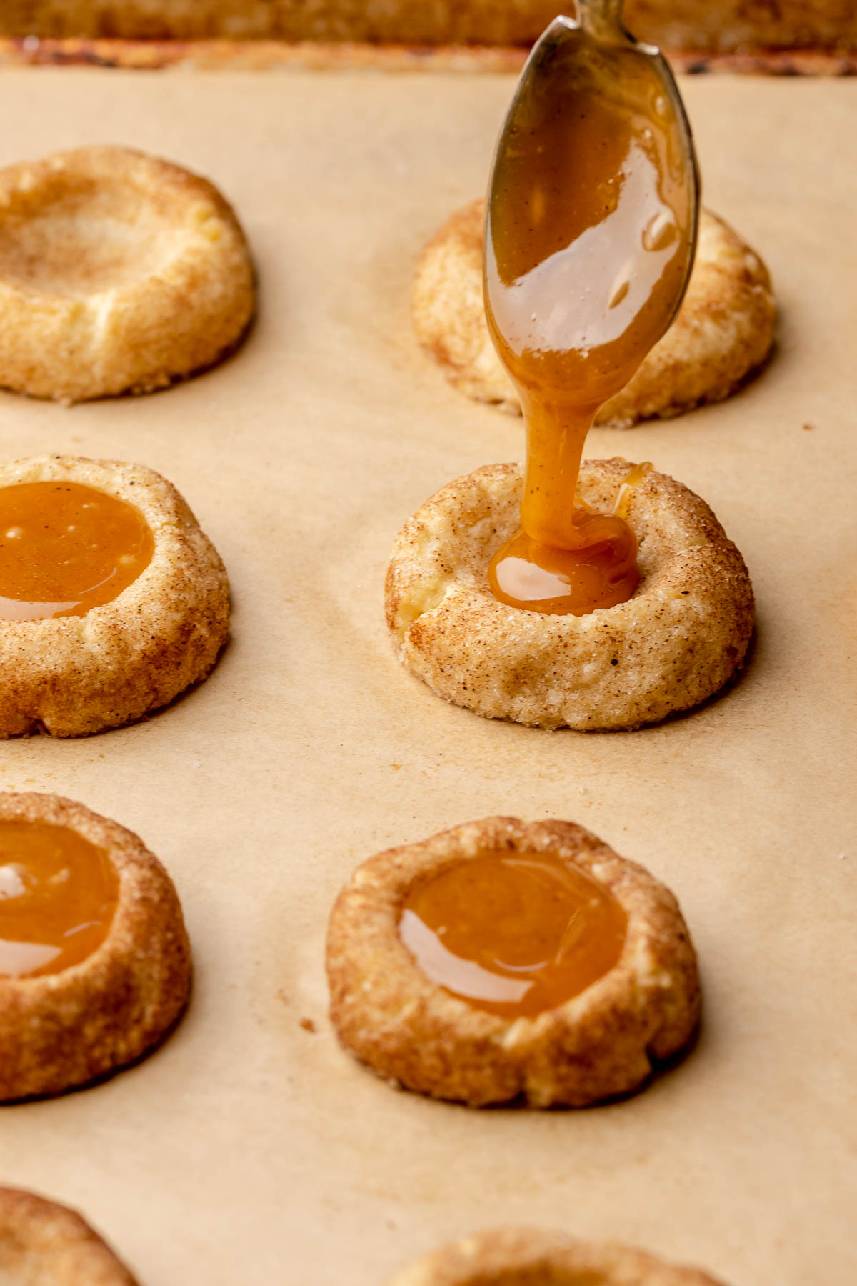 A spoon drizzles apple cider caramel into a cookie.