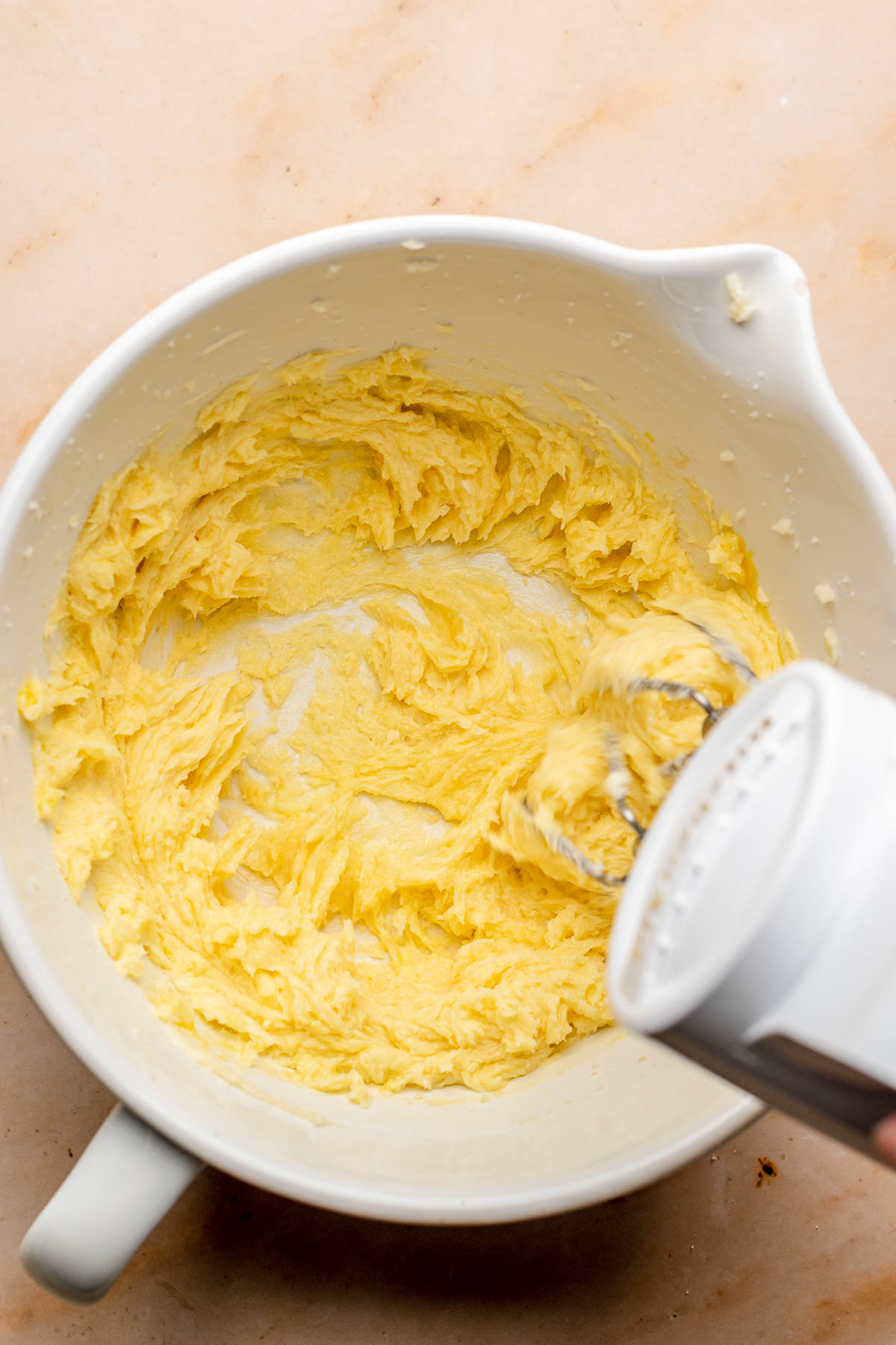 A hand mixer beats cookie dough in a bowl.