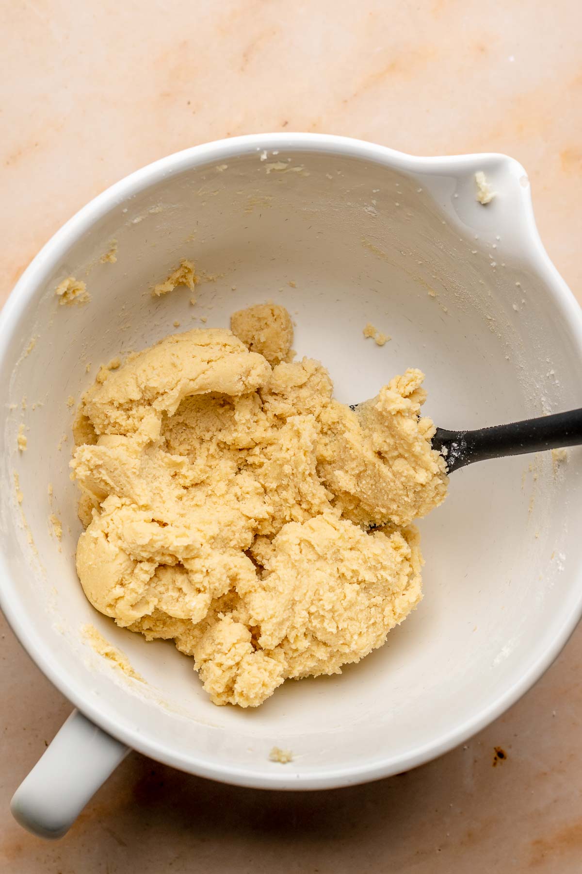 A clump of cookie dough in a bowl with a spatula.