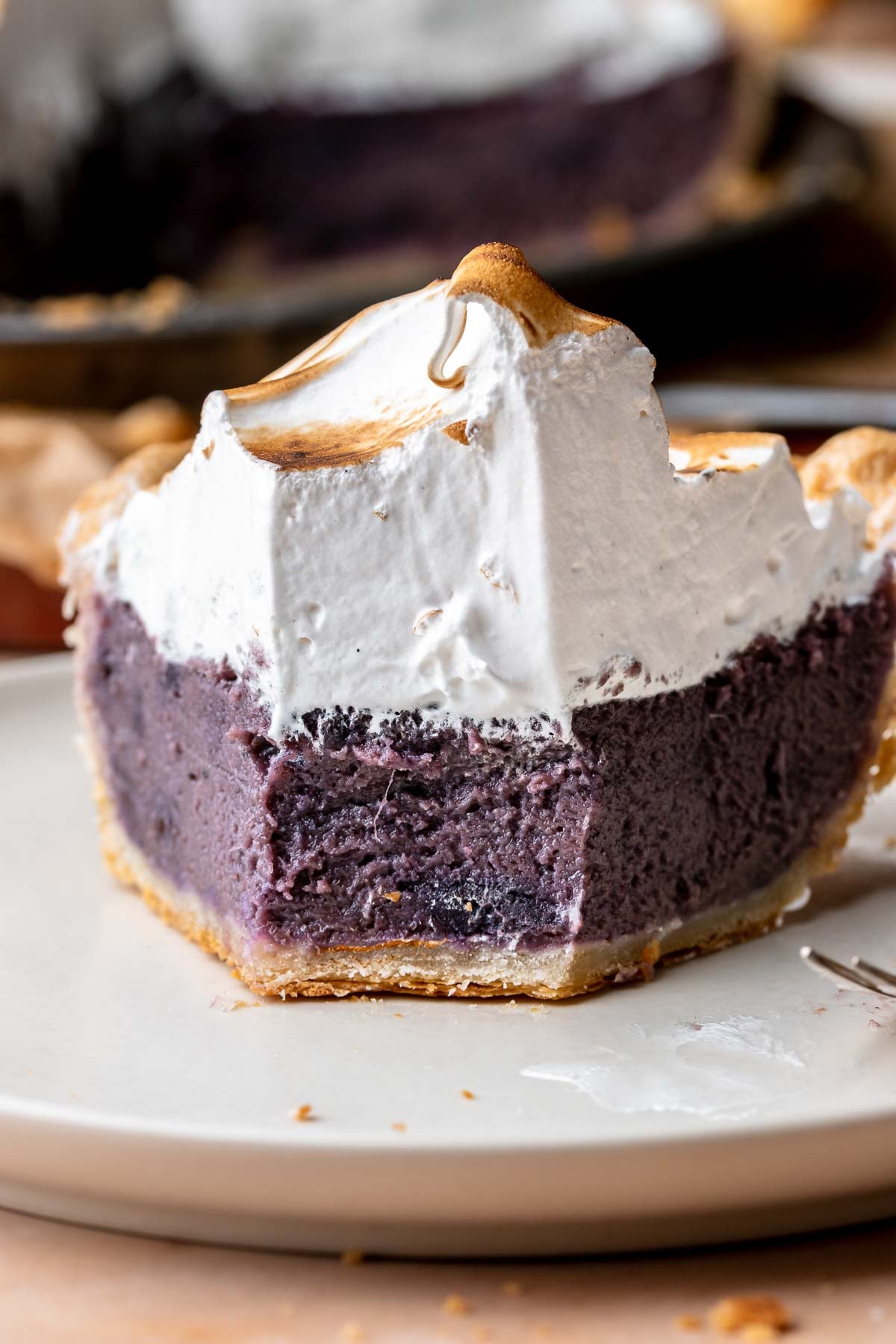 A slice of purple sweet potato pie on a plate. The front bite is removed.