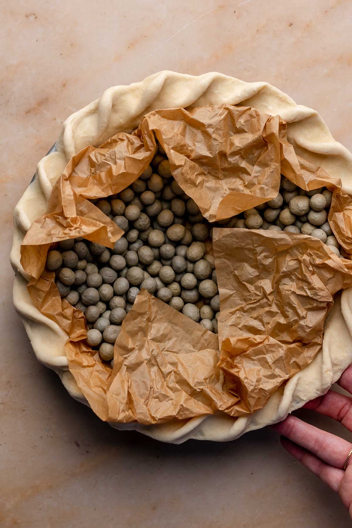 A crimped pie crust filled with parchemnt paper and pie weights.
