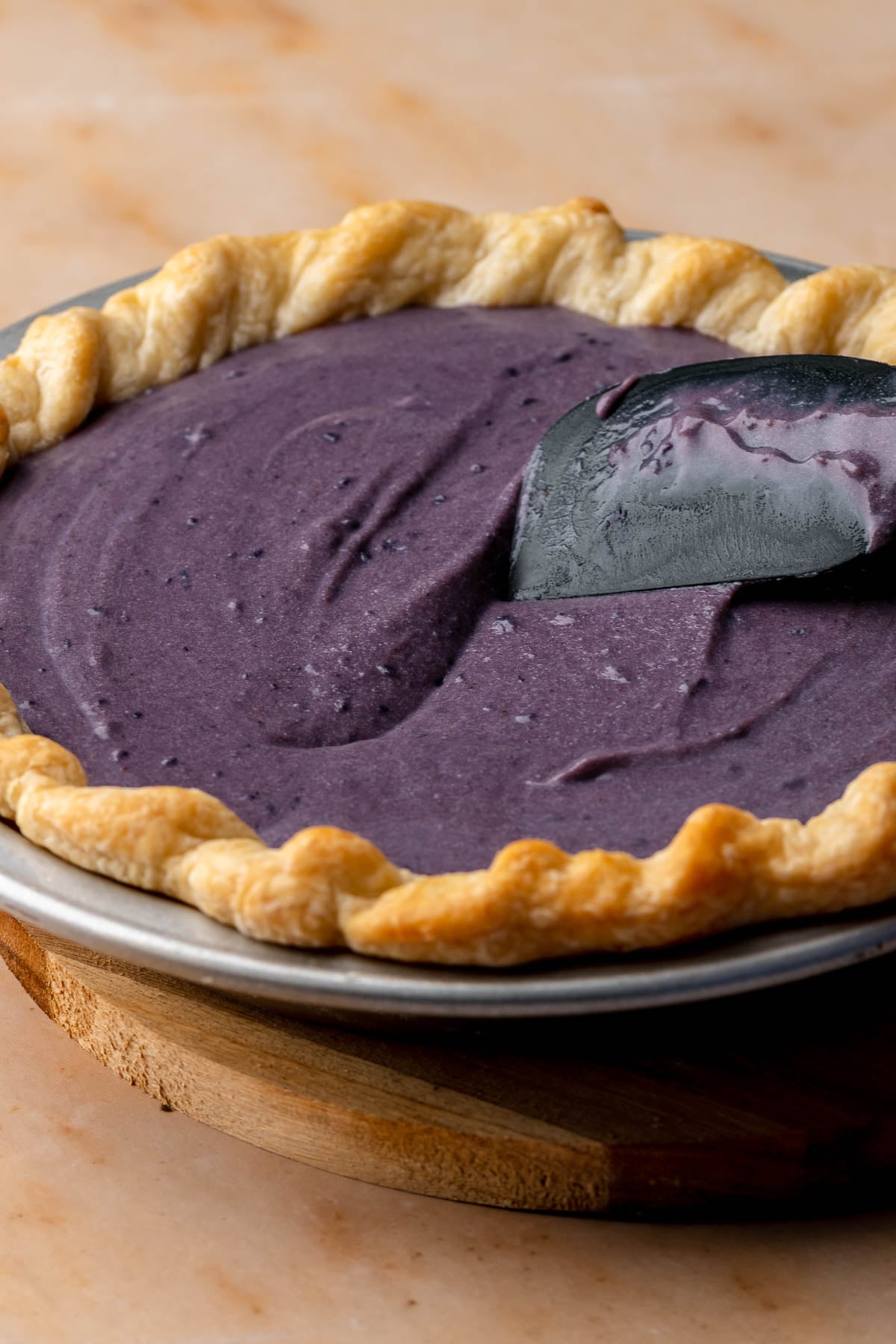 A spatula spreads sweet potato pie filling into the crust.