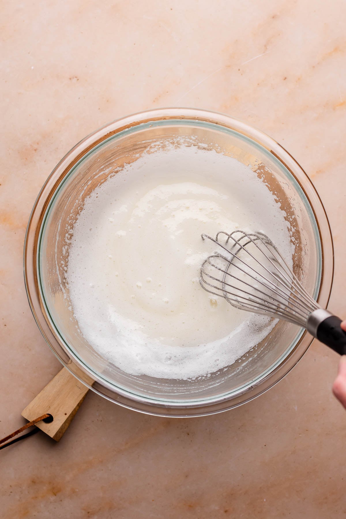 A whisk mixes egg whites in a bowl.