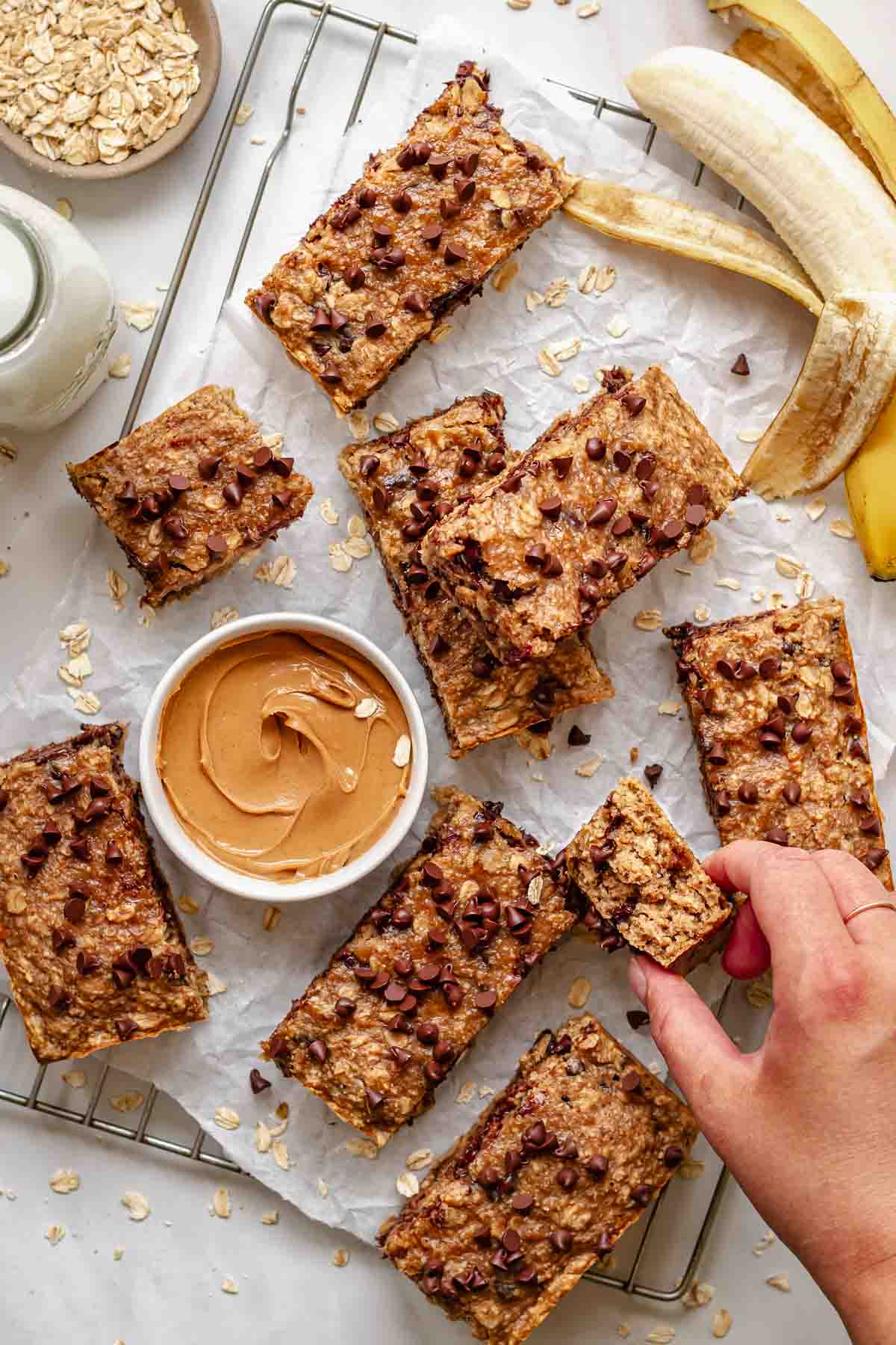 A hand reaches in to take a slice of peanut butter oatmeal bar.
