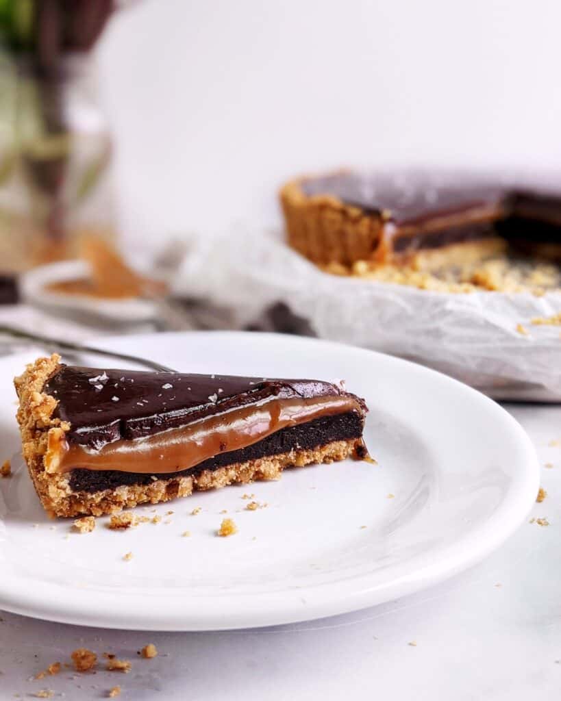 One slice of caramel brownie pretzel pie on a plate with the caramel starting to drip down the side
