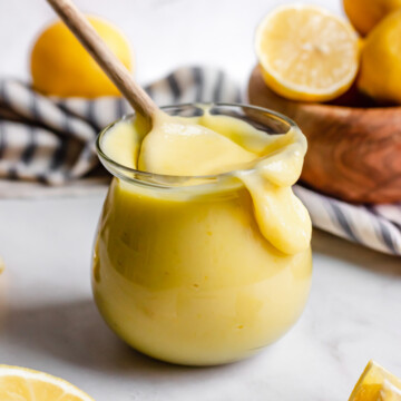 Lemon curd in a jar, spilling over the side.