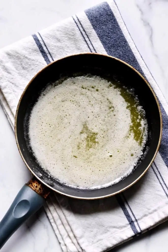 Overhead shot of melted butter in a pan that has started foaming on the top.