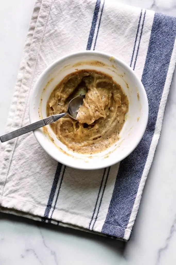 Overhead shot of a bowl of soft brown butter with a spoon in it. 