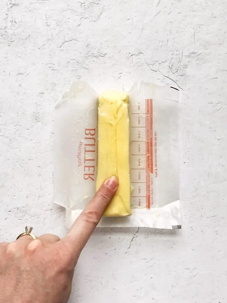 A finger pushing in to a stick of room temperature butter.