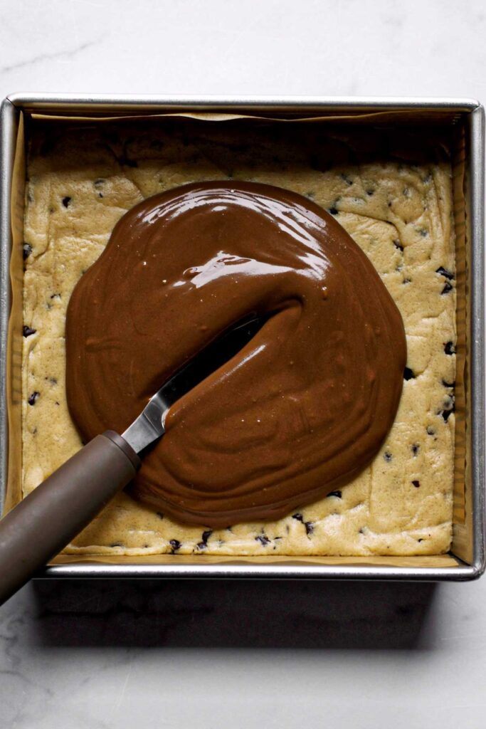 Melted chocolate being spread over the peanut butter cookie dough.