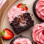 Chocolate strawberry cupcake cut open on a plate to show the chocolate filling.