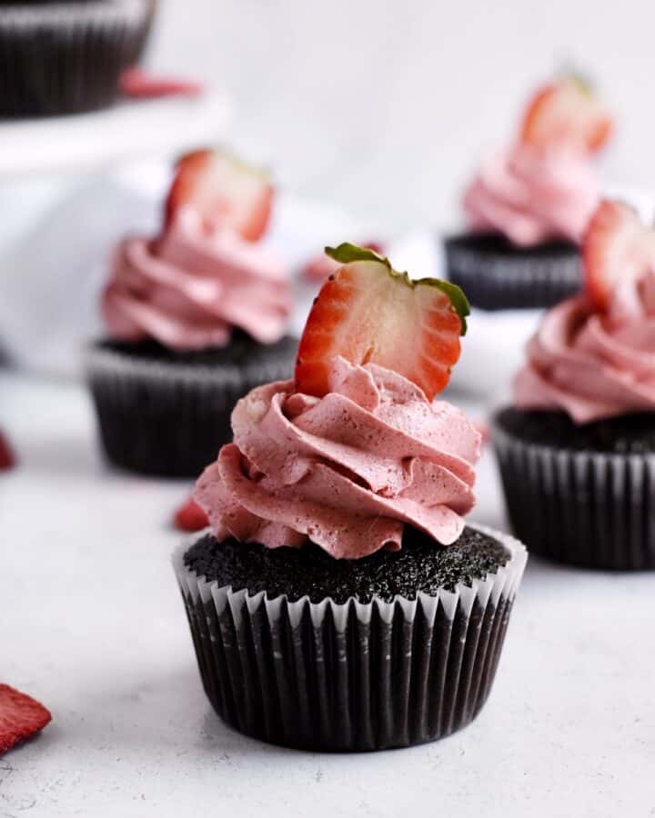 Close up photo of one double chocolate strawberry cupcake with a fresh strawberry on top.