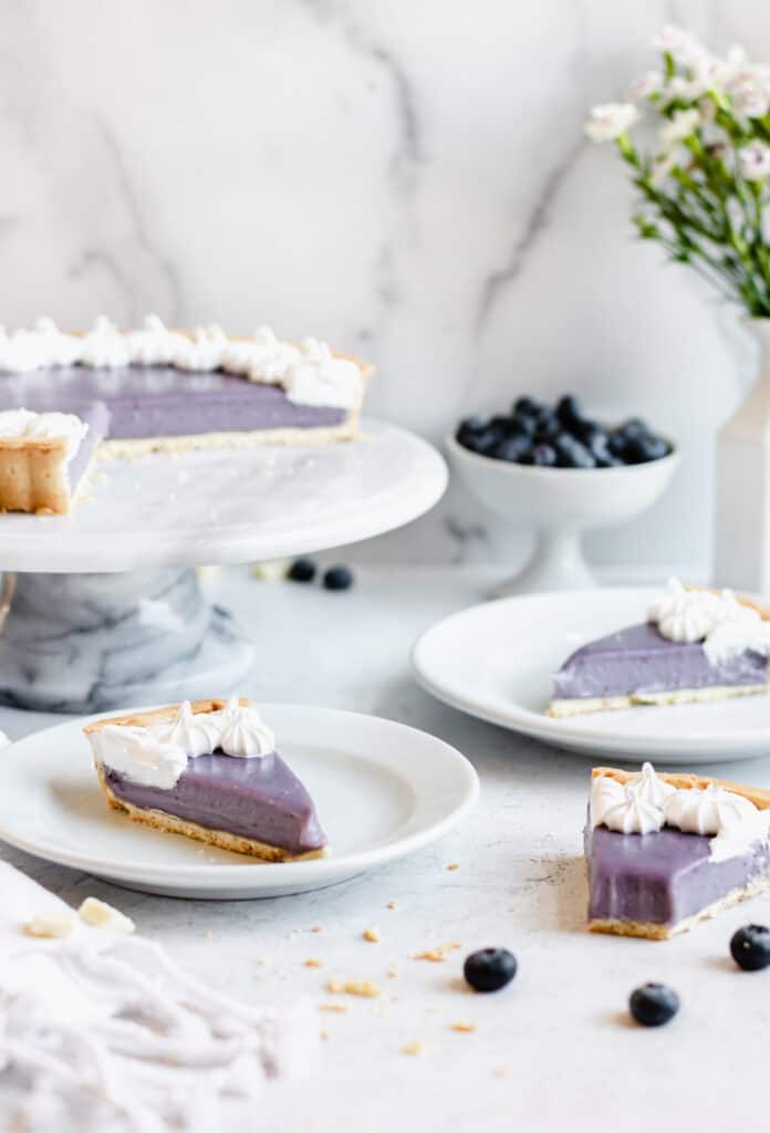 Blueberry white chocolate ganache tart with three slices removed. Two are on plates, one is on the table with a bite removed.