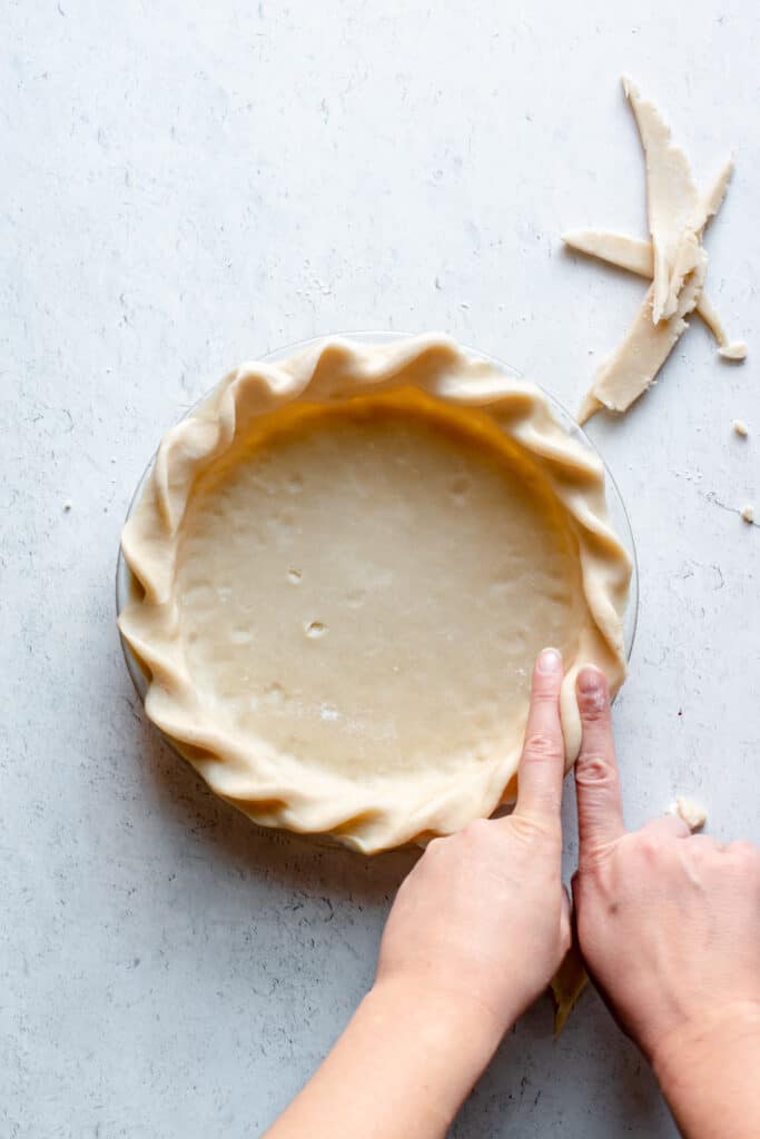 Two fingers create a crimp in the edge of the pie dough