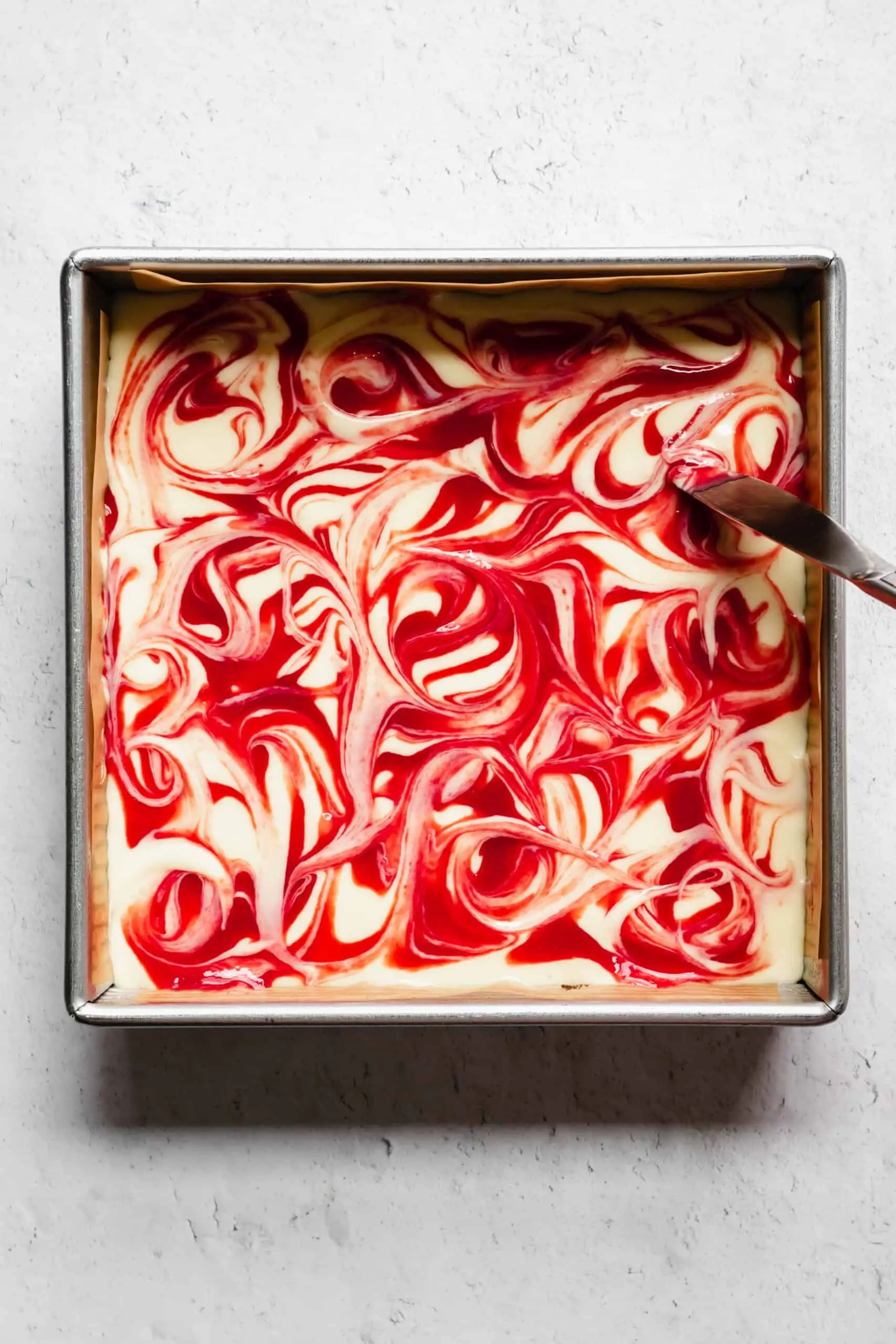 Overhead shot of swirling the raspberry sauce into the batter.