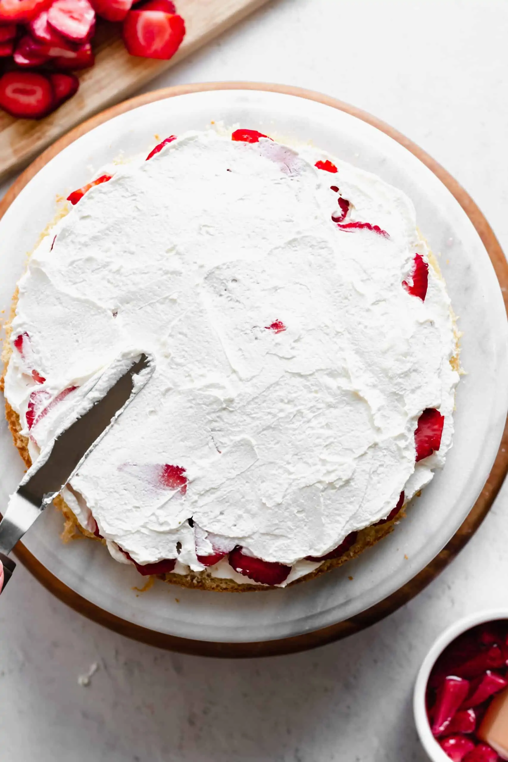 Another layer of whipped cream is added to cover the strawberries.