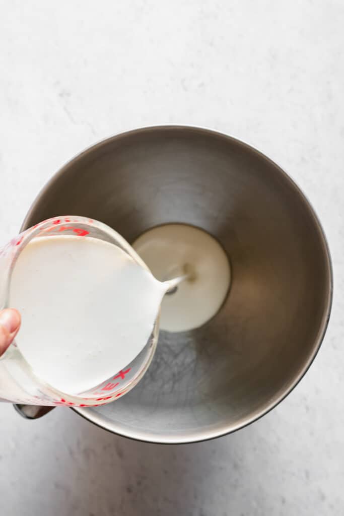 Heavy whipping cream being poured into a mixing bowl