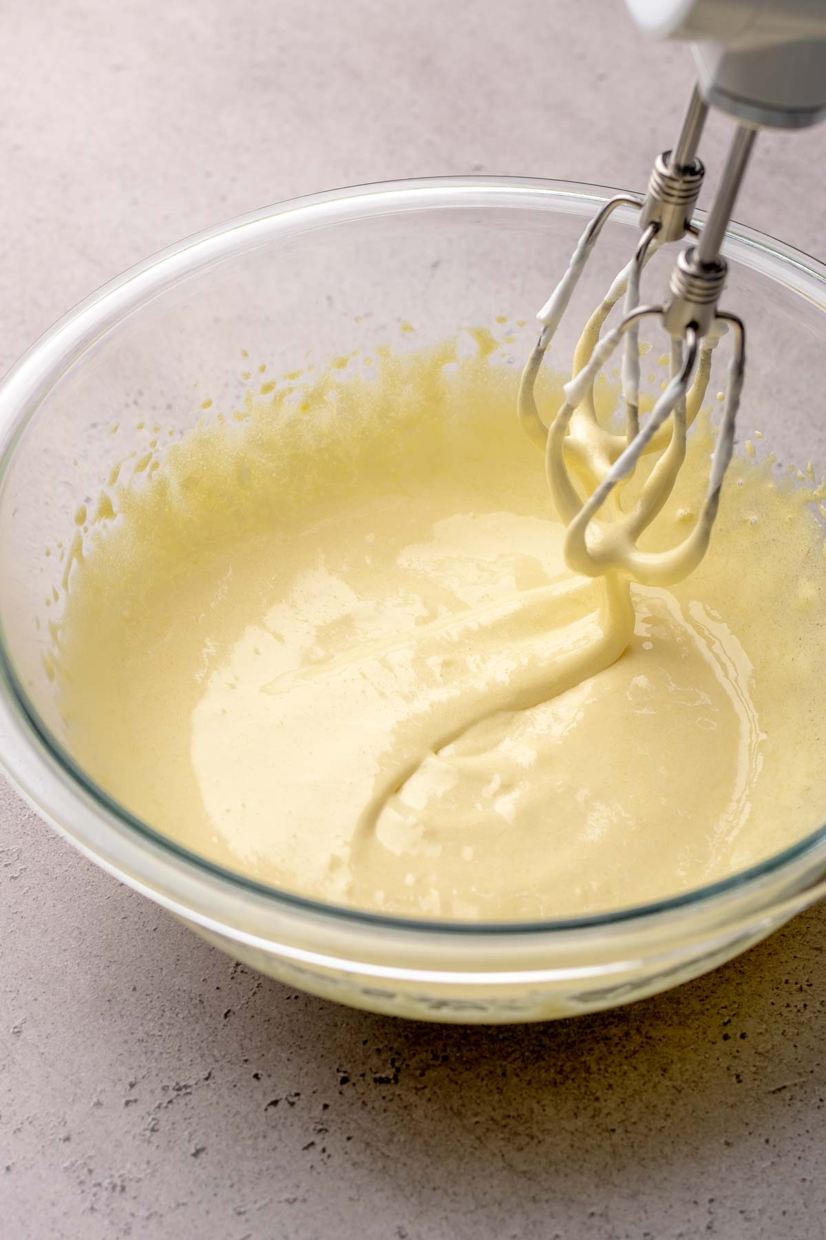 Sponge cake batter falling off of beaters into a bowl.