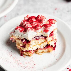 A square slice of cherry tiramisu on a plate with a bite removed.