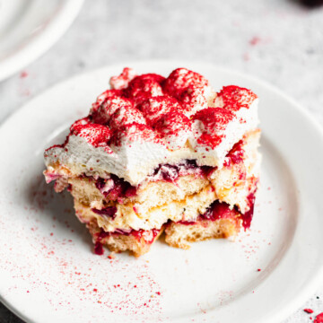 A square slice of cherry tiramisu on a plate with a bite removed.