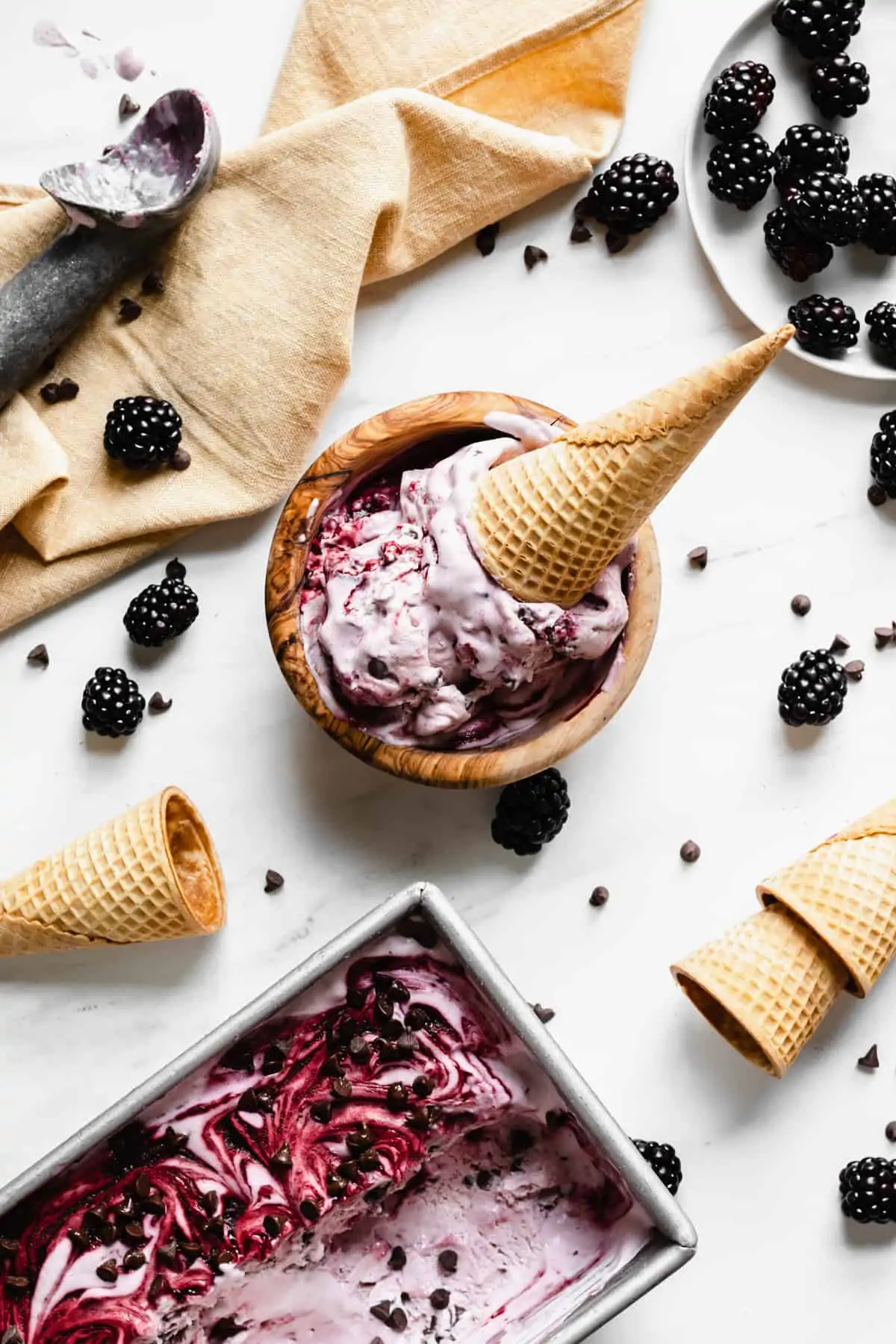 Overhead shot of a bowl of blackberry chip ice cream with a cone sitting inside.