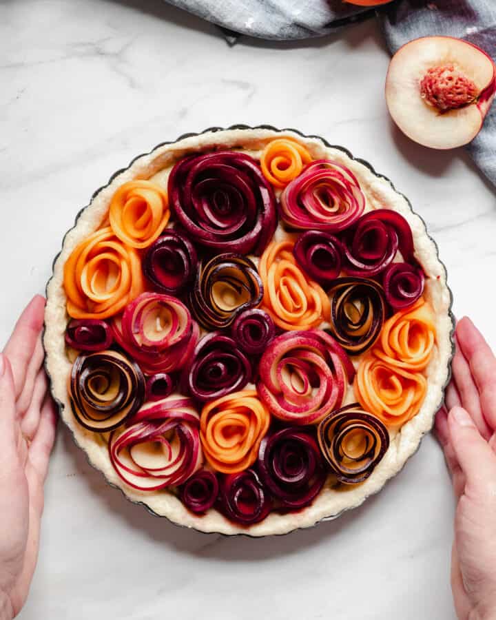 Completed stone fruit tart with roses shot from overhead.