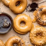 An array of glazed coffee donuts with a cup of coffee next to it.