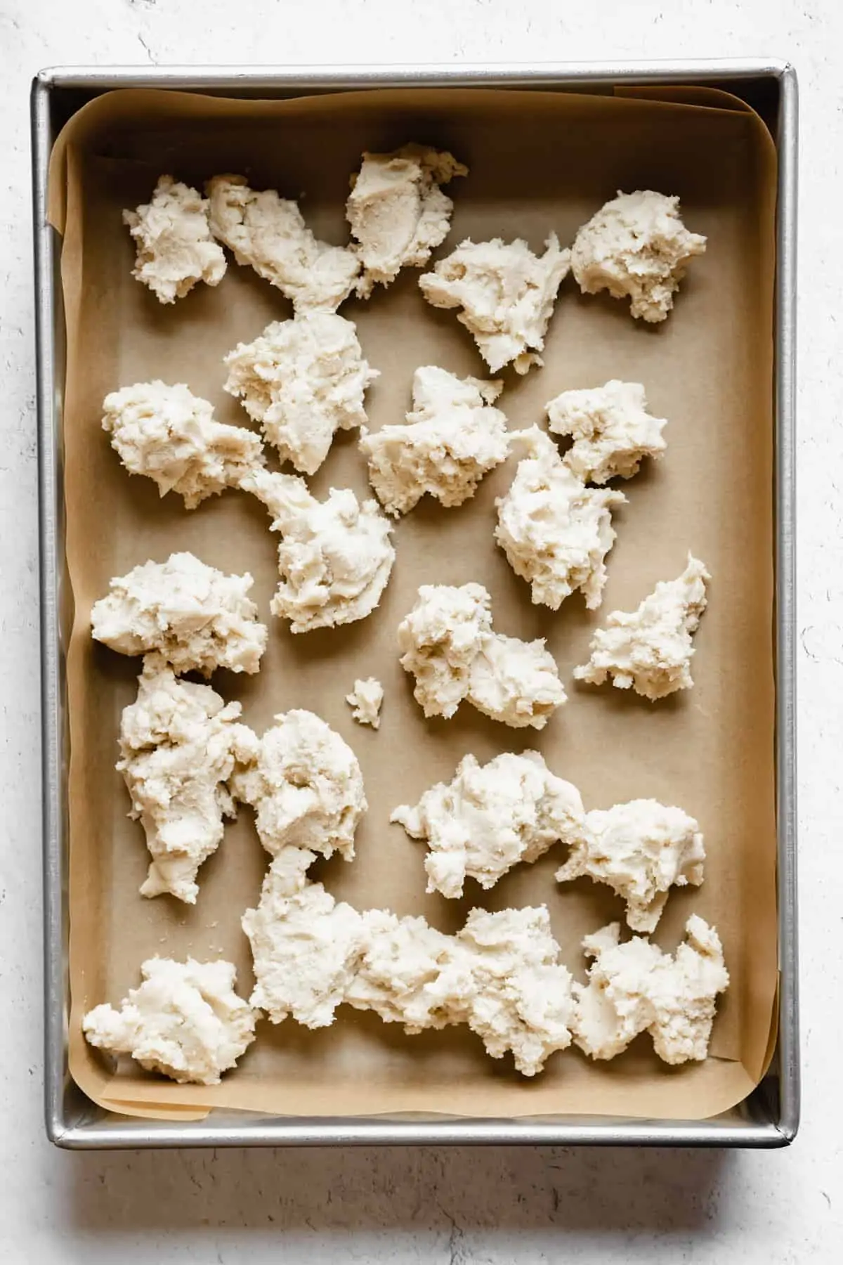 Chunks of shortbread scattered around a prepared pan.