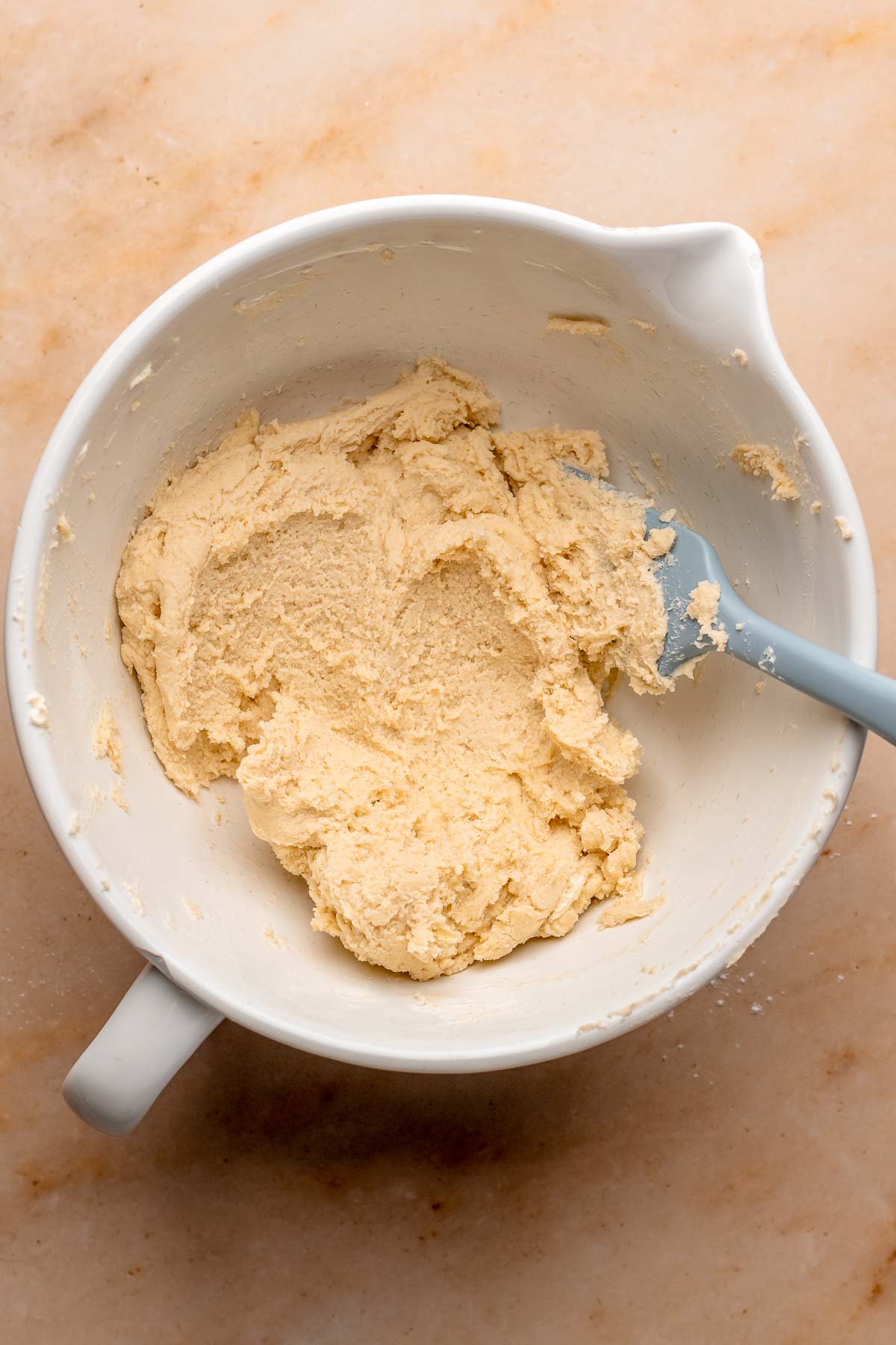 Shortbread dough in a mixing bowl with a spatula.