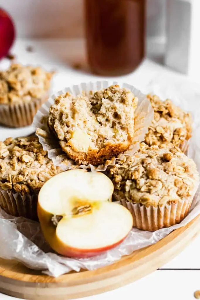 Tray of apple crumble muffins. One has a bite removed sitting on the top.