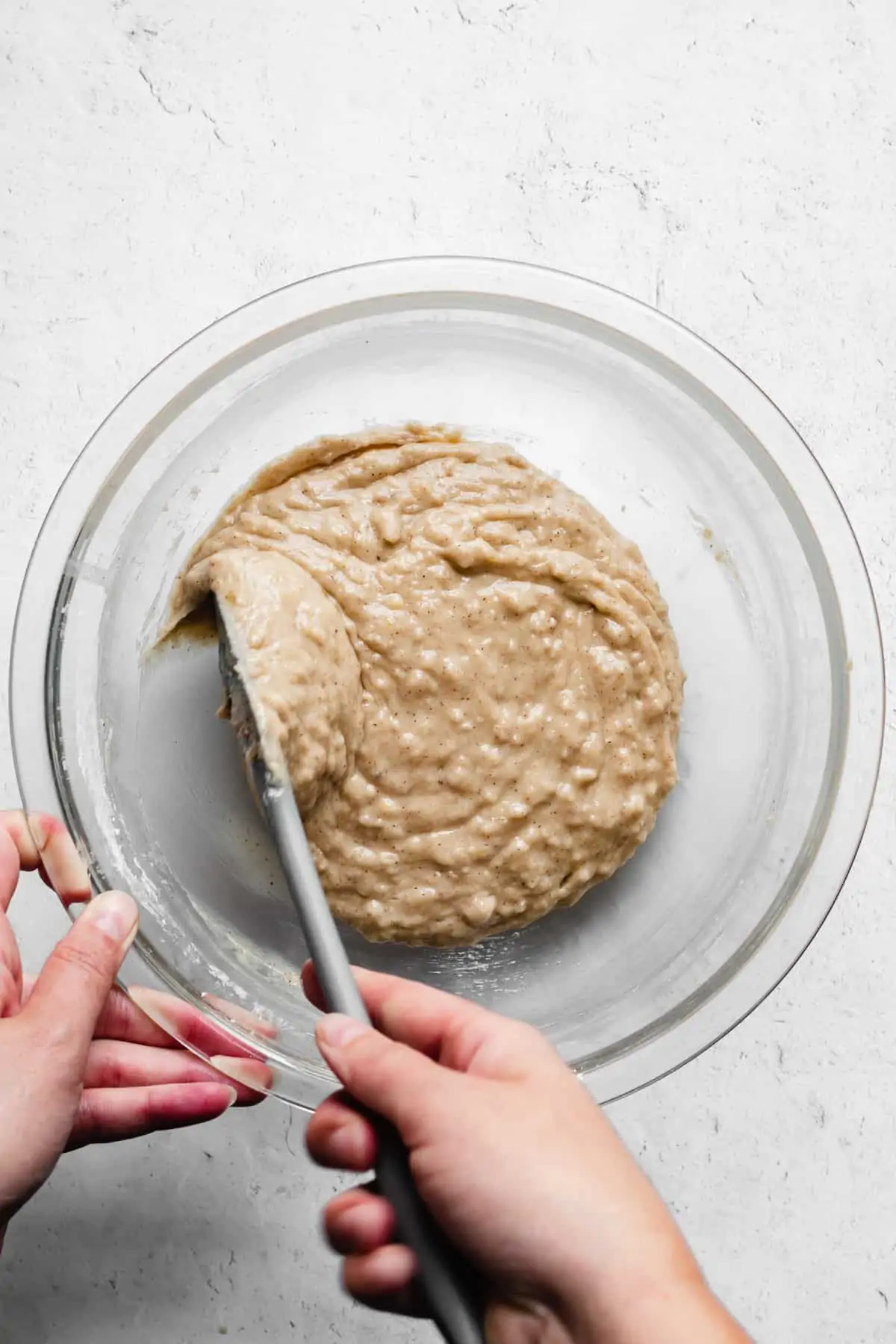 Apple muffin batter being mixed together with a rubber spatula.