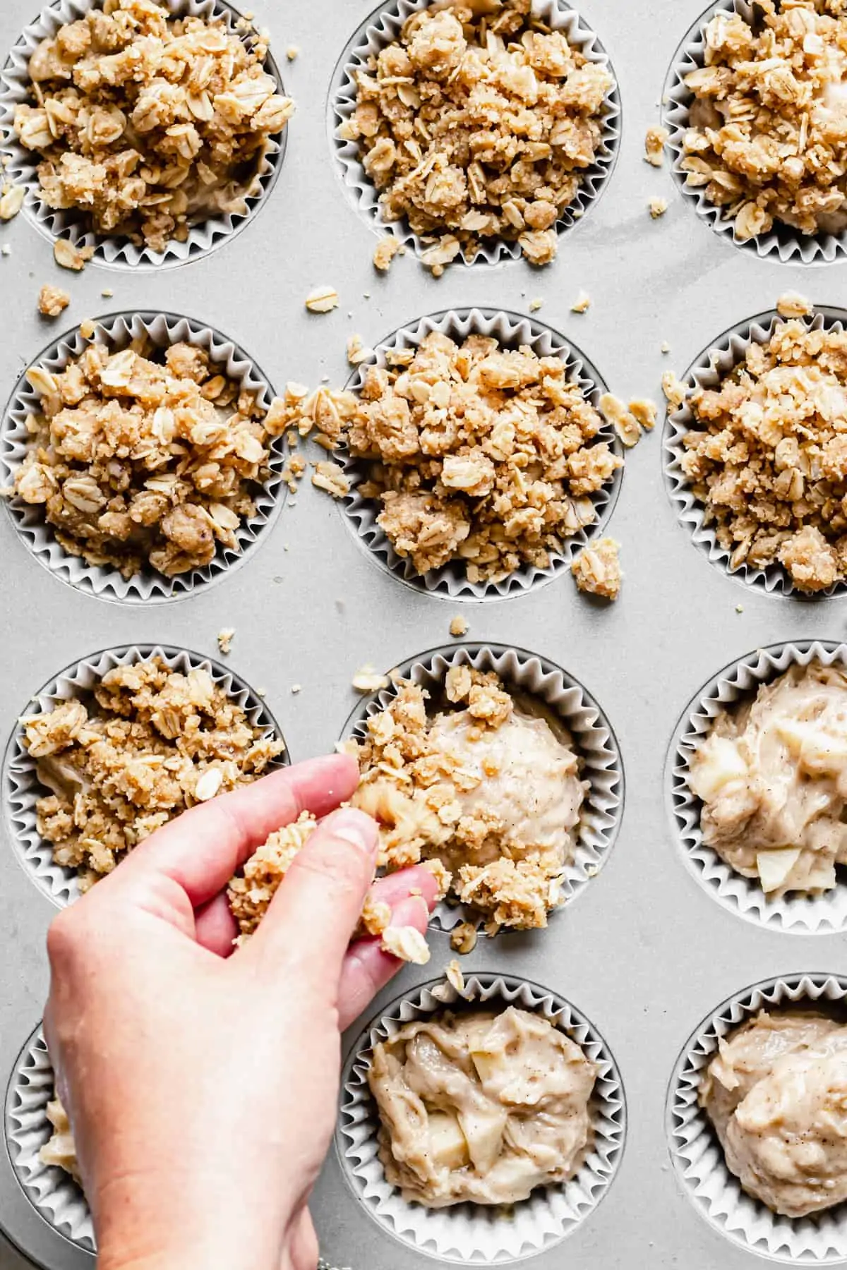 Crumble topping being added to the muffin wells.