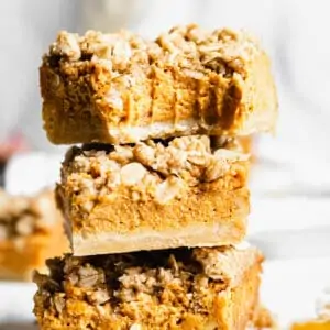 stack of pumpkin pie crumble bars. A bite is removed from the top bar.